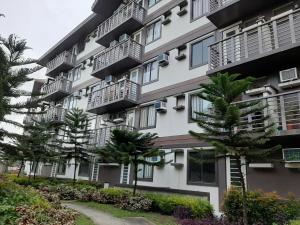 un immeuble d'appartements avec des arbres devant lui dans l'établissement Condo eLgimikero, à Manille