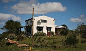 una casa blanca sentada en la cima de un campo en El Rancho de arenas de Jose Ignacio, en José Ignacio