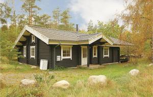 a small black house in the middle of a field at 3 Bedroom Cozy Home In Aakirkeby in Åkirkeby
