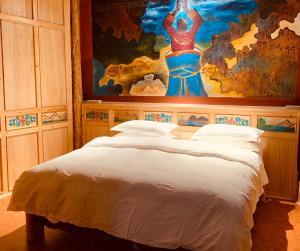 a bedroom with a bed with a painting on the wall at Shangri-La Xiangye Listen to the rain Hotel in Shangri-La