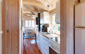 a kitchen with white cabinets and a wooden wall at Holiday Home Æblerosevej in Yderby