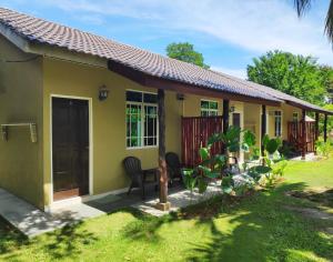 een klein geel huis met stoelen in een tuin bij Sunset Bay Cottage in Tanjung Rhu 