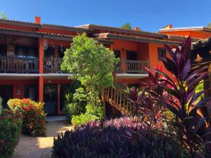 un bâtiment orange avec des plantes devant lui dans l'établissement Vilarejo Do Farol, Praia do Forte, à Praia do Forte