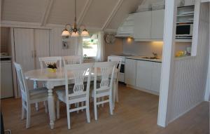 BjerregårdにあるAmazing Home In Hvide Sande With Kitchenのキッチン(白いテーブル、椅子付)
