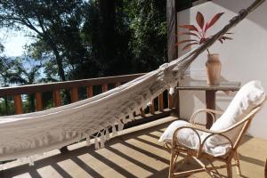 uma rede de descanso num alpendre com uma cadeira e uma mesa em Casa Amaargi Picinguaba em Picinguaba