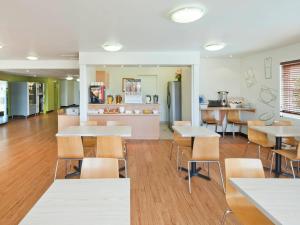 a cafeteria with tables and chairs and a kitchen at ibis Budget Coffs Harbour in Coffs Harbour