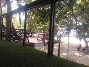 a screened in porch with chairs and a table at Phayam Hostel in Ko Phayam