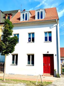 ein weißes Haus mit einer roten Tür in der Unterkunft Werderapartment, FeWo und DZ in Werder + 17 Fotos