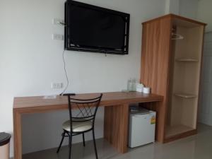 einen Schreibtisch mit Stuhl und einen TV an der Wand in der Unterkunft เคียงเลิงรีสอร์ท in Ban Nong Bua Thong