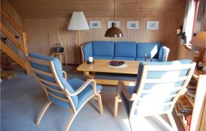 BjerregårdにあるAmazing Home In Hvide Sande With Saunaのリビングルーム(青いソファ、テーブル、椅子付)