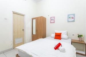 1 dormitorio con cama blanca y almohada roja en RedDoorz Syariah near Assalaam - UMS, en Solo