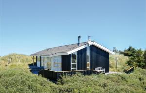 GrønhøjにあるNice Home In Lkken With 3 Bedrooms, Sauna And Wifiの木立の丘の上の黒家