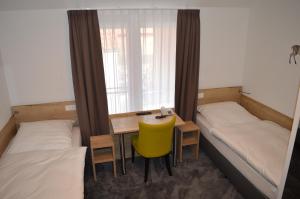 um quarto com 2 camas e uma secretária com uma cadeira amarela em Landgasthof Voltmer em Ramlingen