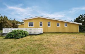 a yellow house with a white fence in a yard at Holiday Home Hvide Sande 48 in Bjerregård