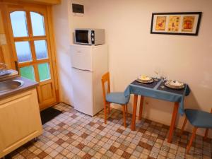a kitchen with a small table and a refrigerator at Tettyei Házikó in Pécs