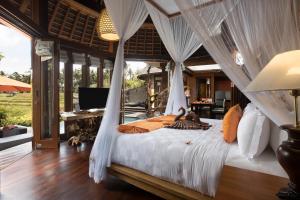 a bedroom with a bed with mosquito netting at Green Field Resort Ubud in Ubud +99 photos