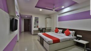 Habitación de hotel con cama y TV en HOTEL OSTRIA, en Surat