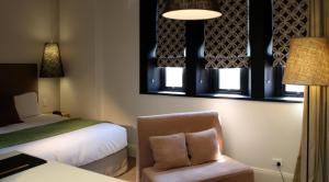 a bedroom with a bed and a chair and windows at Perry Street Hotel in Mudgee