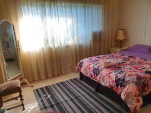 1 dormitorio con 1 cama y una ventana con cortinas en Airport HomeStay, en Perth