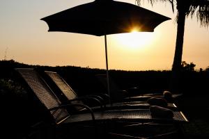 a group of chairs with an umbrella in the sunset at The Ridge Guesthouse in Richards Bay