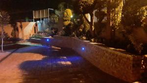 un patio trasero por la noche con luces azules en la pared en Vuya Nathi Bed and Breakfast, en Manzini