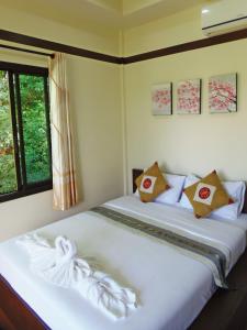 a bedroom with a large white bed with a window at Pai My Guest Resort - SHA Plus in Pai
