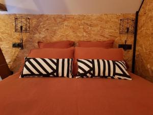 a bedroom with an orange bed with two black and white pillows at Odyssée - Chambre d'hôtes avec spa et sauna privés in Zeggers-Cappel