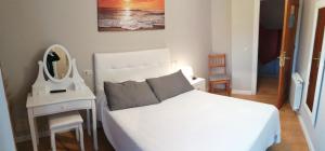 a bedroom with a white bed and a mirror at Hotel Canton in San Vicente de la Barquera