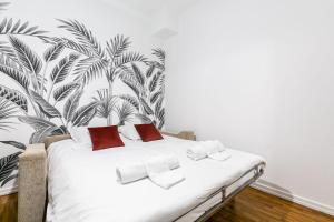 ストラスブールにあるSTRASBOURG HYPER CENTRE 2P de 30m2のトロピカルな壁紙の白いベッドが備わるベッドルーム1室が備わります。