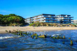 a beach with rocks in the water next to a building at Apartament GOLD Gardenia Dziwnów in Dziwnów