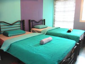 1 dormitorio con 3 camas con sábanas verdes en Sandakan Backpackers Hostel, en Sandakan