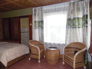 a bedroom with a bed and two chairs and a window at AMBOW Homestay Jungle Trekking & Village Tour in Bukit Lawang