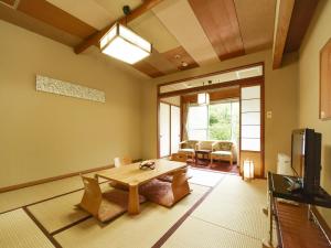 a living room with a table and a tv at Hotel Shikanoyu in Jozankei
