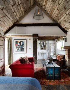 Artist Residence Oxfordshire في أوكسفورد: غرفة معيشة مع أريكة حمراء وطاولة