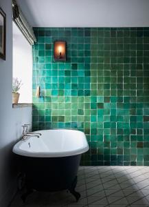a green tiled bathroom with a bath tub in it at Artist Residence Oxfordshire in Oxford