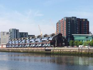 a building on the side of a river with buildings at Riverheights very near SSE Hydro in Glasgow