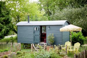 a blue tiny house in a garden with an umbrella at Artist Residence Oxfordshire in Oxford
