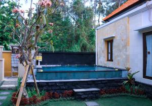 a swimming pool in a yard next to a house at Kubu Kapas Bali in Ubud