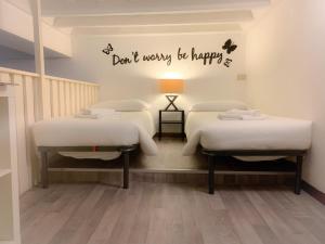 two beds in a room with a sign that says dont worry be happy at Luxury barberini boutique Apartment in Rome