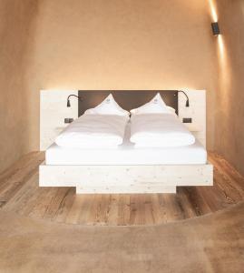 Cama blanca en una habitación con suelo de madera en Dietrichhof a bsunders Platzl en Feldthurns