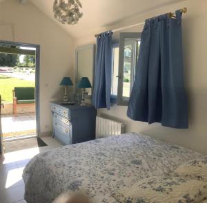um quarto com cortinas azuis, uma cama e uma janela em Grande villa d'exception en Normandie tennis, piscine, jacuzzi, salle de fitness em Muids