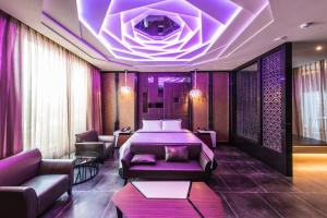une chambre d'hôtel avec un lit et un éclairage violet dans l'établissement Voga Motel, à Taichung