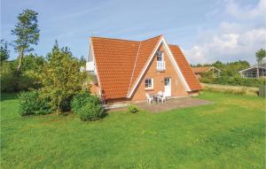 HalbyにあるBeautiful Home In Skjern With 3 Bedrooms, Sauna And Wifiの庭に椅子2脚が付いたオレンジの屋根の家