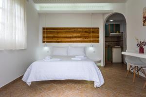 a bedroom with a large white bed and a kitchen at Orizontes Studios in Adamantas