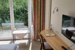 a living room with a wooden table and a television at Landgasthof/Hotel Hirsch im Grünen in Mehrstetten