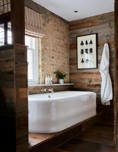 a white bath tub in a room with a brick wall at Artist Residence London in London
