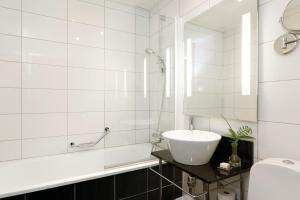 a white bathroom with a sink and a tub at Elite Grand Hotel Norrköping in Norrköping