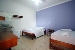 a room with two beds and a sink in it at Pousada Flor de Lis in Olímpia