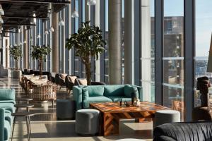a lobby with couches and tables and windows at The Collective Canary Wharf in London