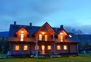 a large wooden house with lights on at Agroturystyka Trzy Siostry in Stronie Śląskie